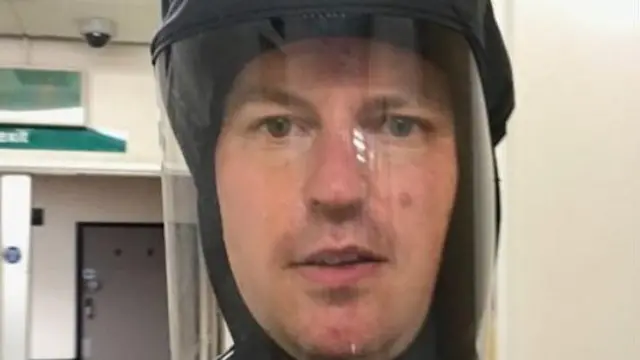 A man in a protective mask looks at the camera