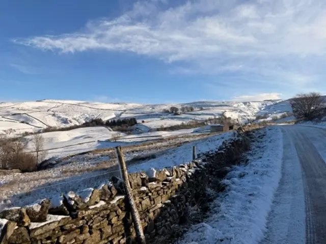 A snow-filled country road in a rural setting