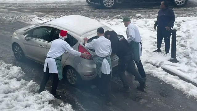 A team of butchers help push a tranded car on an icy road