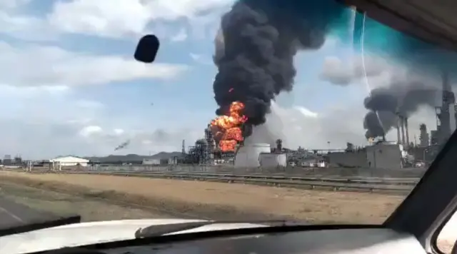 A screengrab from a video taken inside a car showing the fire at the plant and a thick cloud of black smoke