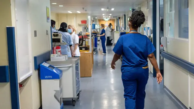 A nurse walks along a hospital corridor