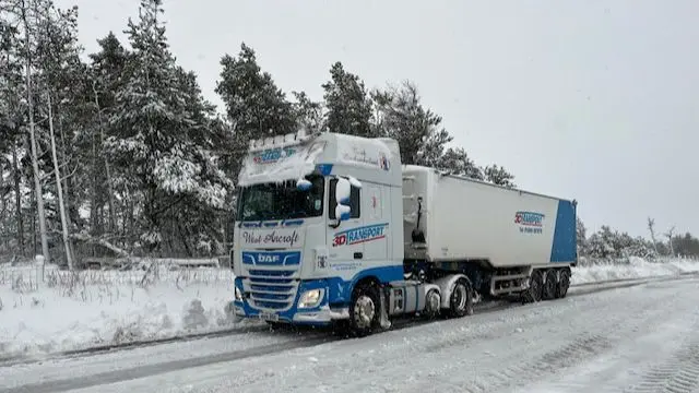 Truck stopped on an icy road in front of snow-covered trees