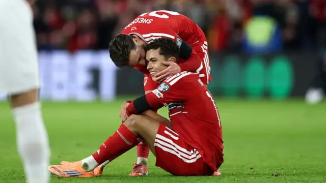 Brennan Johnson of Wales sat on the floor smiling after victory against North Macedonia