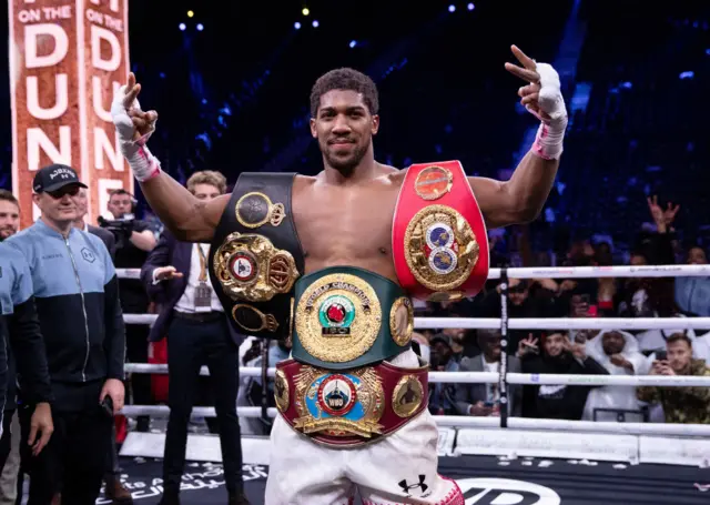 Anthony Joshua with the heavyweight world titles wrapped around his torso