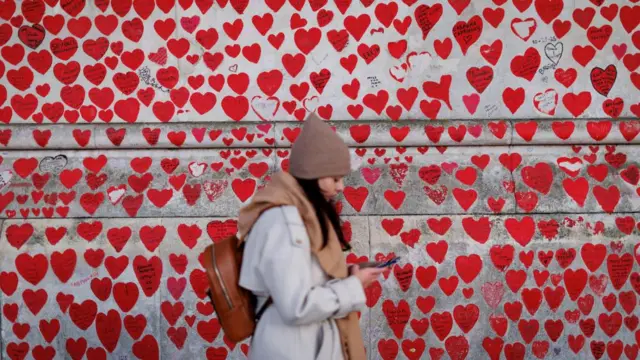 A woman walks past the Covid memorial wall in London