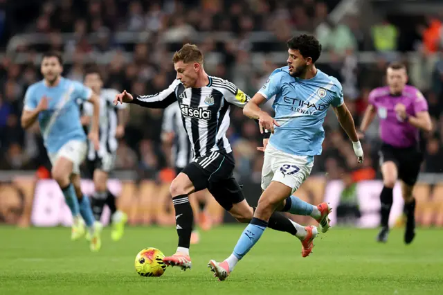 Harvey Barnes of Newcastle United is put under pressure by Matheus Nunes of Manchester City during the Premier League match between Newcastle United and Manchester City at St James' Park on November 22, 2025 in Newcastle upon Tyne, England.