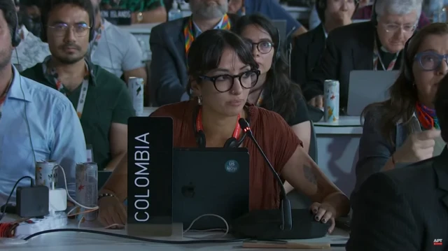 Delegate for Colombia mid-speech. She's a young woman with black hair pulled back in a ponytail and thick rimmed glasses