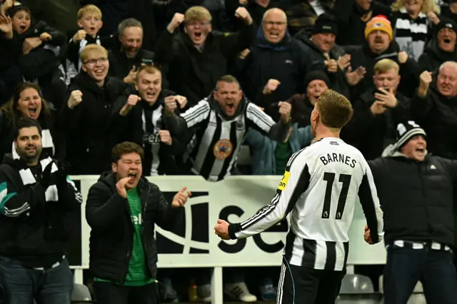 Newcastle United's English midfielder #11 Harvey Barnes celebrates with fans after scoring the opening goal during the English Premier League football match between Newcastle United and Manchester City at St James' Park in Newcastle-upon-Tyne, north east England on November 22, 2025.