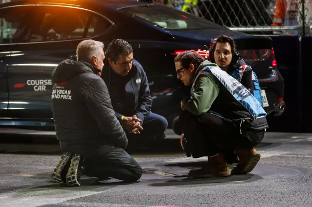 Track officials inspect a manhole cover that came loose after a car passed over it during second practice for the Las Vegas Grand Prix