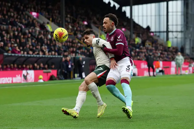 Pedro Neto of Chelsea is challenged by Quilindschy Hartman of Burnley during the Premier League match between Burnley and Chelsea at Turf Moor on November 22, 2025 in Burnley, England.