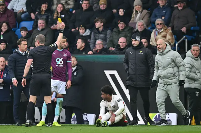 Chelsea's Italian head coach Enzo Maresca (R) receives a yellow card (L) after a tackle on Chelsea's Brazilian midfielder #17 Andrey Santos (C-on ground) during the English Premier League football match between Burnley and Chelsea at Turf Moor in Burnley, north-west England on November 22, 2025.