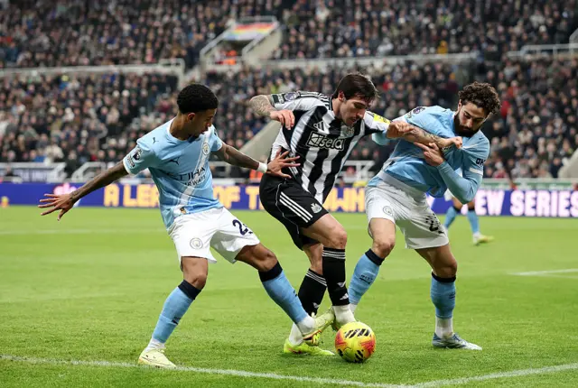 Sandro Tonali of Newcastle United is challenged by Savinho (L) and Josko Gvardiol of Manchester City (R) during the Premier League match between Newcastle United and Manchester City at St James' Park on November 22, 2025 in Newcastle upon Tyne, England.