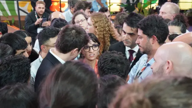 Several people stand in a huddle in deep discussion