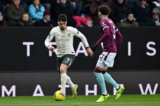 Pedro Neto of Chelsea is challenged by Quilindschy Hartman of Burnley during the Premier League match between Burnley and Chelsea at Turf Moor on November 22, 2025 in Burnley, England.