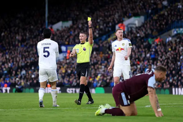 Match referee, Robert Jones shows Pascal Struijk of Leeds United a yellow card following a foul on Ross Barkley of Aston Villa during the Premier League match between Leeds United and Aston Villa at Elland Road on November 23, 2025 in Leeds, England.