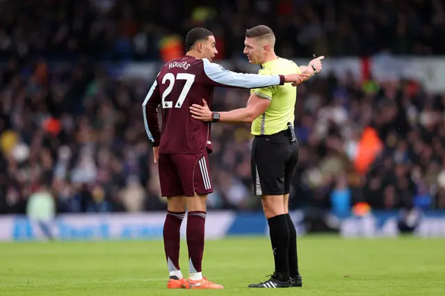 Morgan Rogers of Aston Villa speaks with Referee Robert Jones during the Premier League match between Leeds United and Aston Villa at Elland Road on November 23, 2025 in Leeds, England.