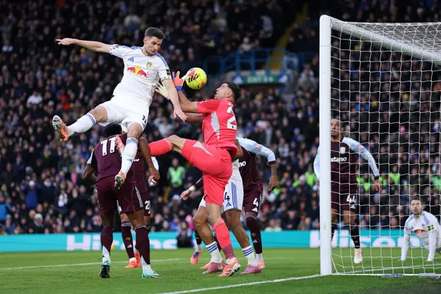Anton Stach of Leeds United battles for possession with Emiliano Martinez of Aston Villa before Lukas Nmecha of Leeds United scores his team's first goal during the Premier League match between Leeds United and Aston Villa at Elland Road on November 23, 2025 in Leeds, England.