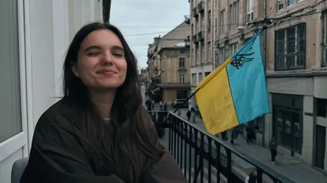 Woman smiling whilst sat on a balcony