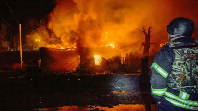 Firefighter looks upon building set ablaze