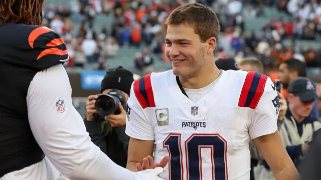 New England Patriots quarterback Drake Maye shakes hands with Cincinnati Bengals offensive tackle Amarius Mims