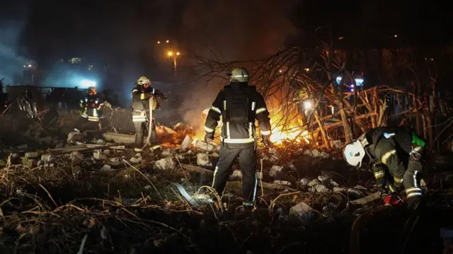 Rescue workers at a site in Kharkiv dig through rubble near a fire