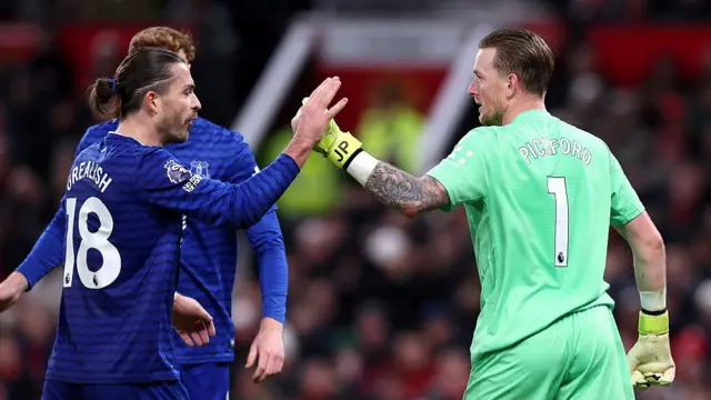 Jack Grealish high fives team-mate Jordan Pickford