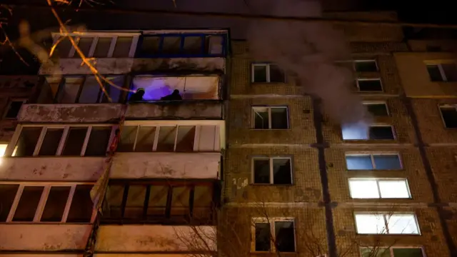 A firefighter assists a resident during an evacuation at the site of an apartment building