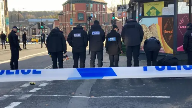 Police officers examine the scene on London Road in Sheffield