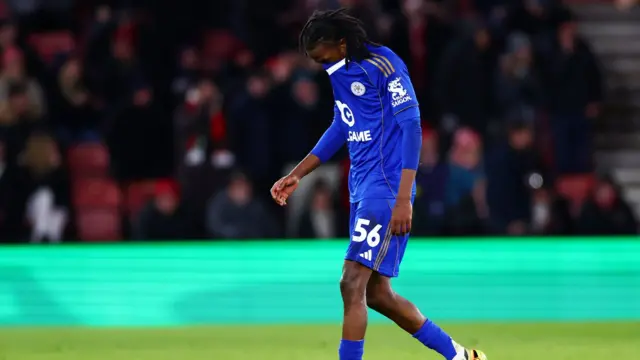 Olabade Aluko tries to hide his face with his shirt as he leaves the field following his red card