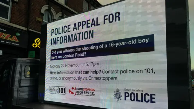 A mobile digital billboard parked on a street displays a police appeal for information about the shooting of a 16-year-old boy on London Road.