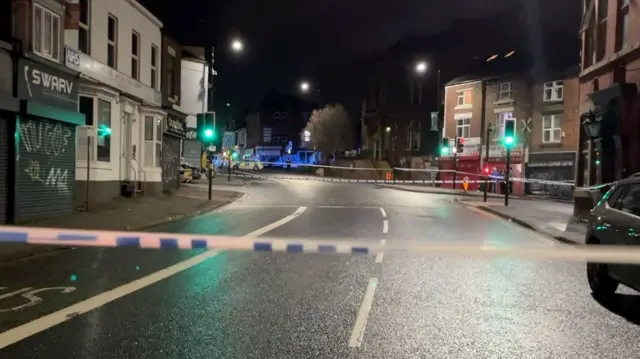 Two cordons section off part of a street at night