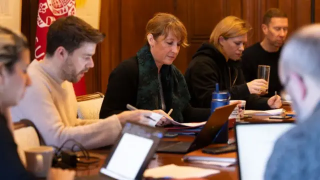 Rachel Reeves with laptops and documents next to civil servants