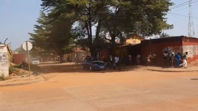 Around a dozen people running down a street in Bissau city