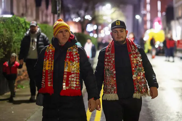 Two Liverpool fans with badges on their scarves