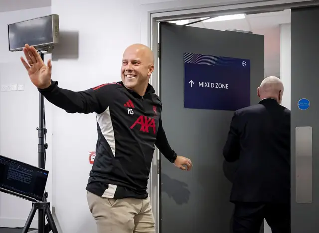 Arne Slot waving before walking out of a door