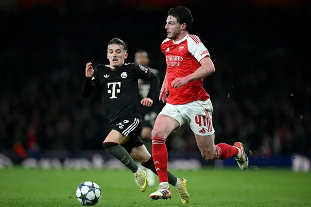Declan Rice of Arsenal runs with the ball whilst under pressure from Lennart Karl of Bayern Munich