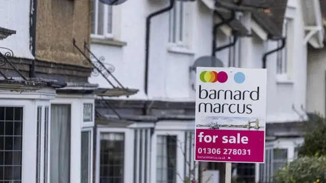 A for sale sign in front of row of terraced houses
