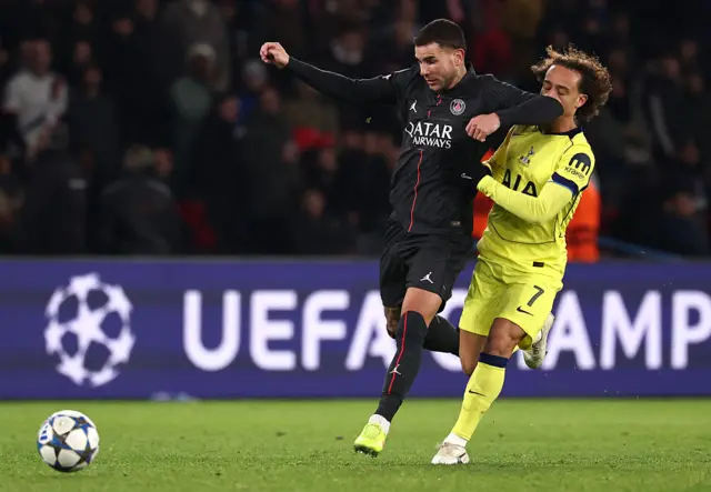 Paris Saint-Germain's Lucas Hernandez (L) fouls Tottenham's Xavi Simons (R)