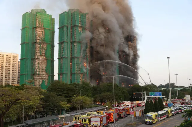 Long distance shot showing blocks on fire with multiple fire engines in the foreground