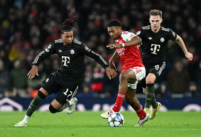 Myles Lewis-Skelly of Arsenal is challenged by Michael Olise of Bayern Munich