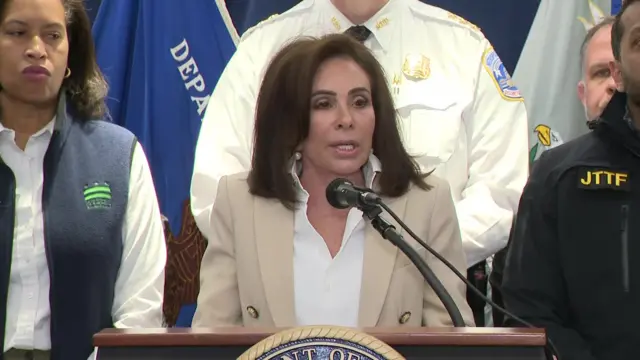 Jeanine Pirro pictured wearing a beige blazer in front of the podium