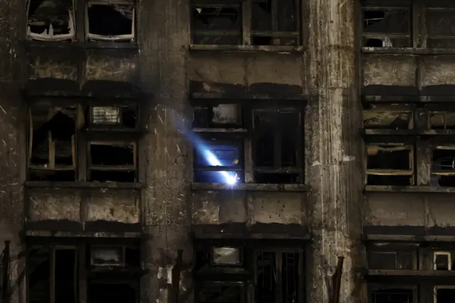 A rescuer works inside a damaged building at the scene after a deadly fire at the Wang Fuk Court
