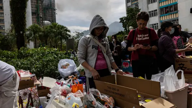 People go through food near residential buildings that continue to burn at Wang Fuk Court in the Tai Po district