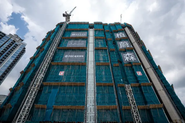 A scaffolding-wrapped high-rise building seen from below