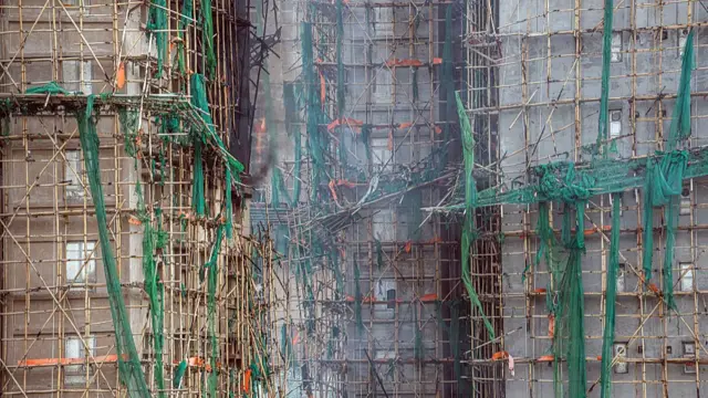 Styrofoam boarded windows behind scaffolding and netting at a smouldering residential building at the Wang Fuk Court in the Tai Po district of Hong Kong, China, on Thursday, 27 November 2025.