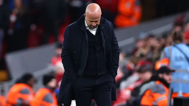 Liverpool manager Arne Slot puts his head down towards the ground while stood on the touchline.