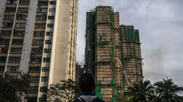 Firefighters hose down a smouldering residential building at the Wang Fuk Court in the Tai Po district of Hong Kong, China