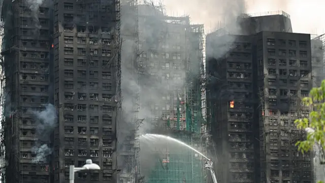 Firefighters spray water on flames as a major fire burns through several apartment blocks at the Wang Fuk Court residential estate in Hong Kong's Tai Po district
