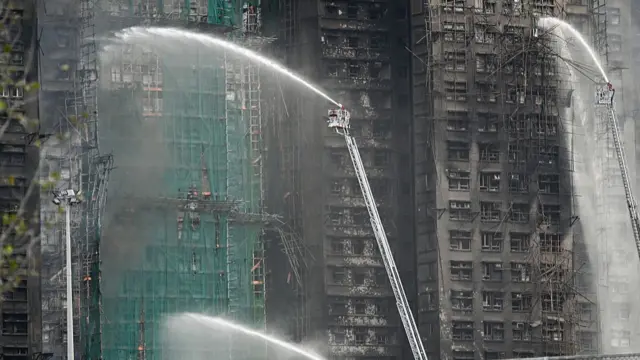 Firefighters spray water on flames as a major fire burns through several apartment blocks at the Wang Fuk Court residential estate in Hong Kong's Tai Po district
