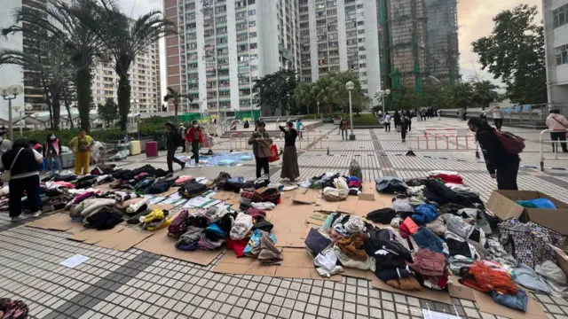 Bundles of clothes are stacked on the ground on pieces of cardboard